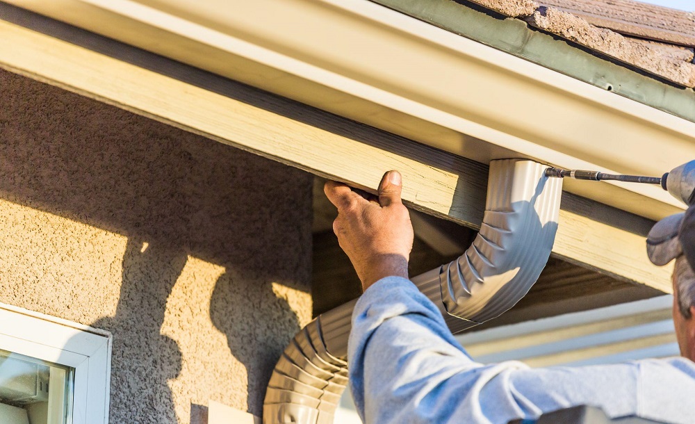 man installing gutter pipes