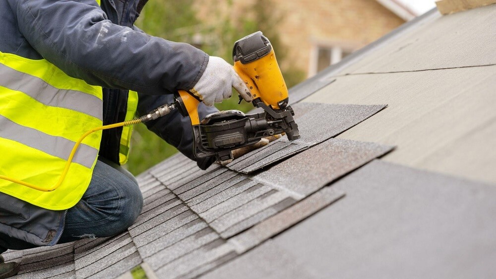 man installing roof with nailgun